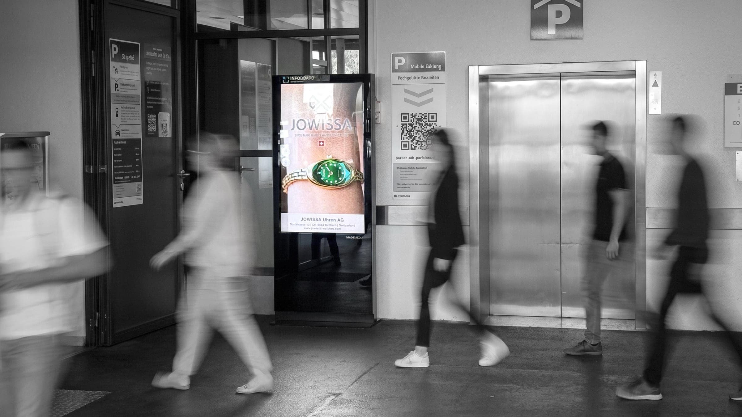Infoboard-Stele mit Uhrenwerbung im Eingangsbereich eines Parkhauses